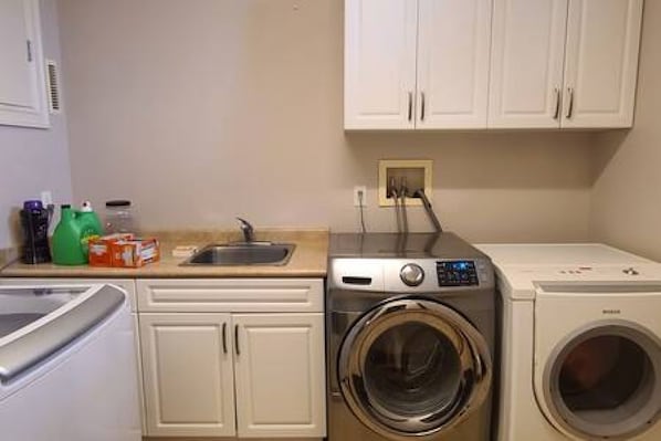 A laundry area with a washing machine, a dryer, and a sink.