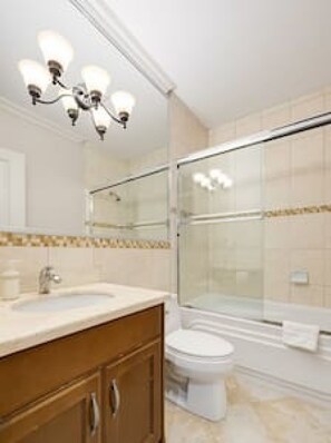 Un baño moderno con cabina de ducha de vidrio, tocador con lavabo e inodoro.