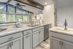 A kitchen with a large window, a ceiling fan, and a dishwasher. - Comfortable Cabin w/ Hot Tub, Near Old Midtown (Ruidoso)