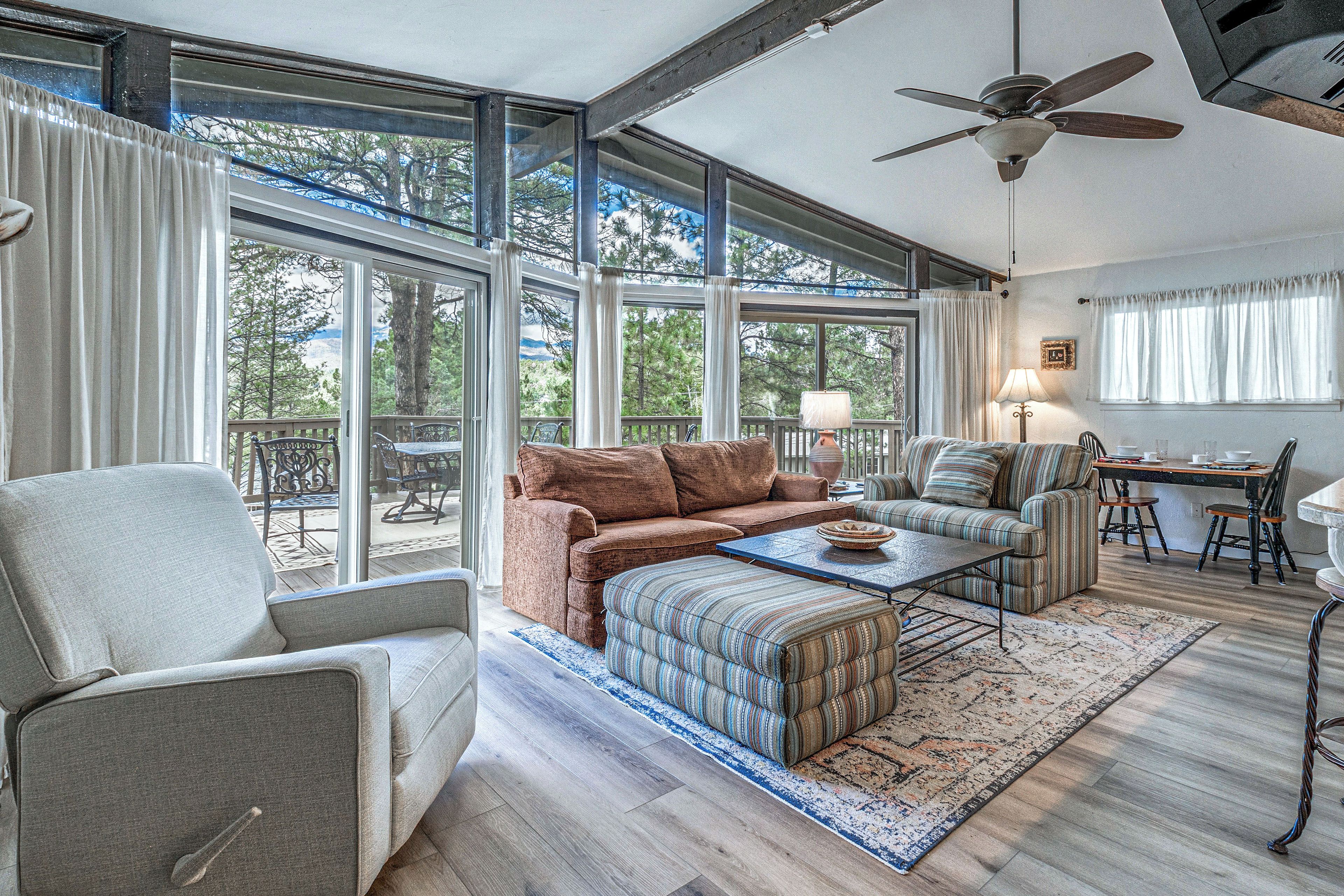 A spacious living room with a large window, a ceiling fan, and a cozy seating area.