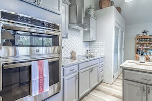 A modern kitchen with stainless steel appliances, a herringbone tile backsplash, and a wine rack. - Comfortable Cabin w/ Hot Tub, Near Old Midtown (Ruidoso)