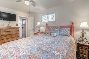 A bedroom with a bed, dresser, nightstands, a television, and a window. - Comfortable Cabin w/ Hot Tub, Near Old Midtown (Ruidoso)