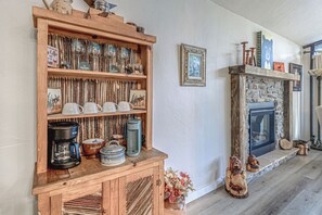 A wooden shelf with glassware and a coffee maker, a fireplace with decorative items, and a rustic wall. - Comfortable Cabin w/ Hot Tub, Near Old Midtown (Ruidoso)