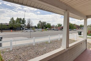 Un espacio al aire libre techado con cerca blanca, camino pavimentado y automóviles estacionados.