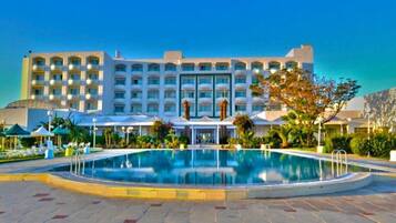 A hotel with a large pool, multiple balconies, and a well-maintained garden.