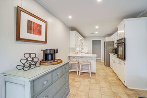 A modern kitchen with white cabinetry, a coffee machine, and a framed picture on the wall. - Charming Tulsa Home Near Lafortune Park (Tulsa)