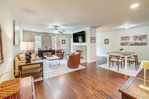 A spacious living room with a fireplace, a dining area with a table and chairs, and a kitchen in the background. - Private Workout Studio & Fenced Yard! Tulsa Escape (Tulsa)