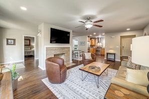 A spacious living room with a fireplace, leather armchair, and a dining area. - Private Workout Studio & Fenced Yard! Tulsa Escape (Tulsa)