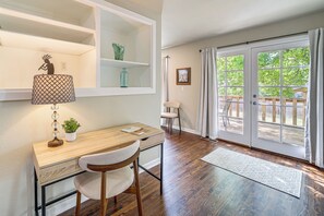 A room with a wooden desk, a chair, a lamp, a shelf with decorative items, a framed picture on the wall, and a large sliding glass door leading to an outdoor area. - Private Workout Studio & Fenced Yard! Tulsa Escape (Tulsa)