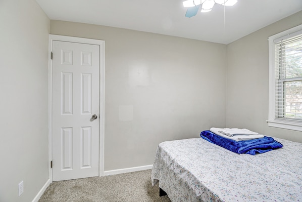 Un dormitorio con una cama individual, una puerta y una ventana con persianas.