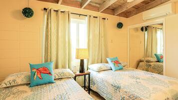 Un dormitorio con dos camas, una ventana con cortinas, una lámpara de noche y un espejo.