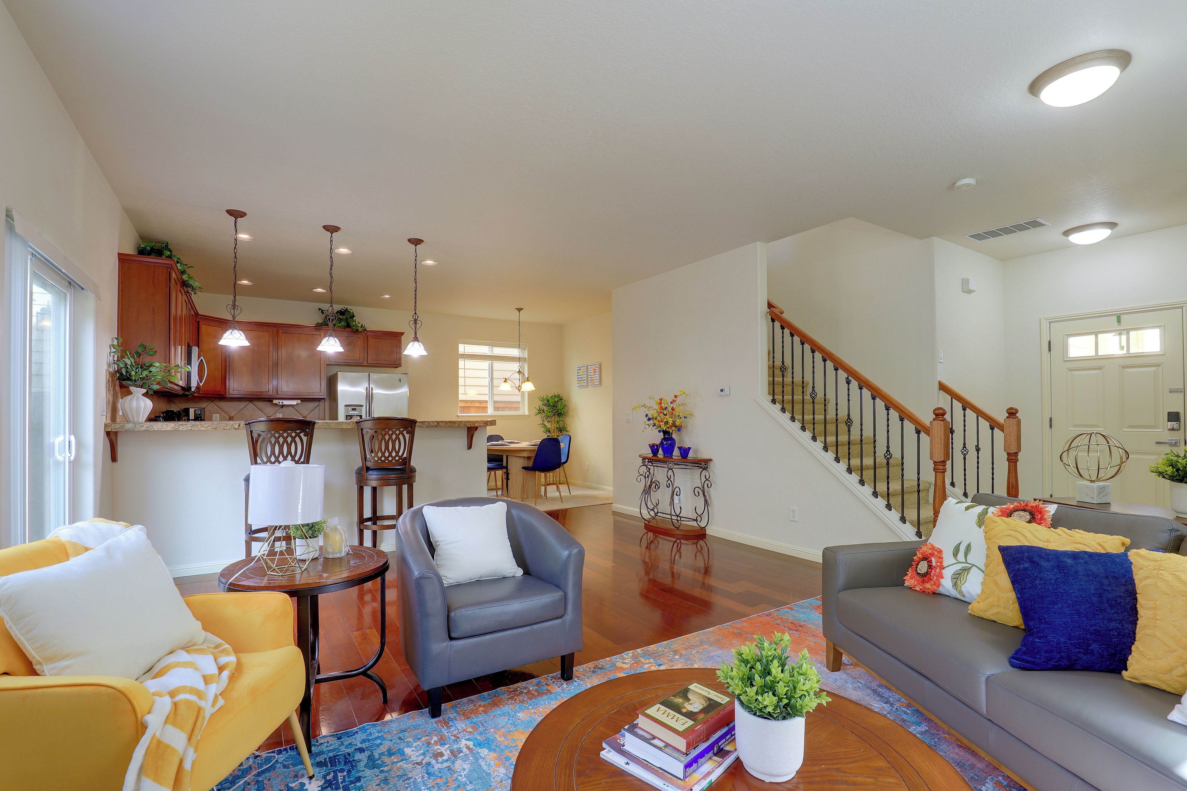 A spacious living room with a dining area, kitchen, and staircase.