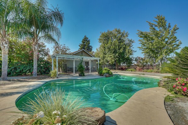 A backyard with a swimming pool, a covered patio, and various trees and plants. - Private Pool! Charming Clovis Escape (Clovis)