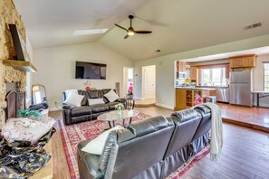 A spacious living area with a fireplace, leather sofas, a flat-screen TV, and a kitchen with wooden cabinets and a stainless steel refrigerator. - Private Pool! Charming Clovis Escape (Clovis)