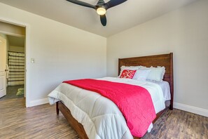 A bedroom with a bed, a ceiling fan, and a door leading to a bathroom. - Private Pool! Charming Clovis Escape (Clovis)