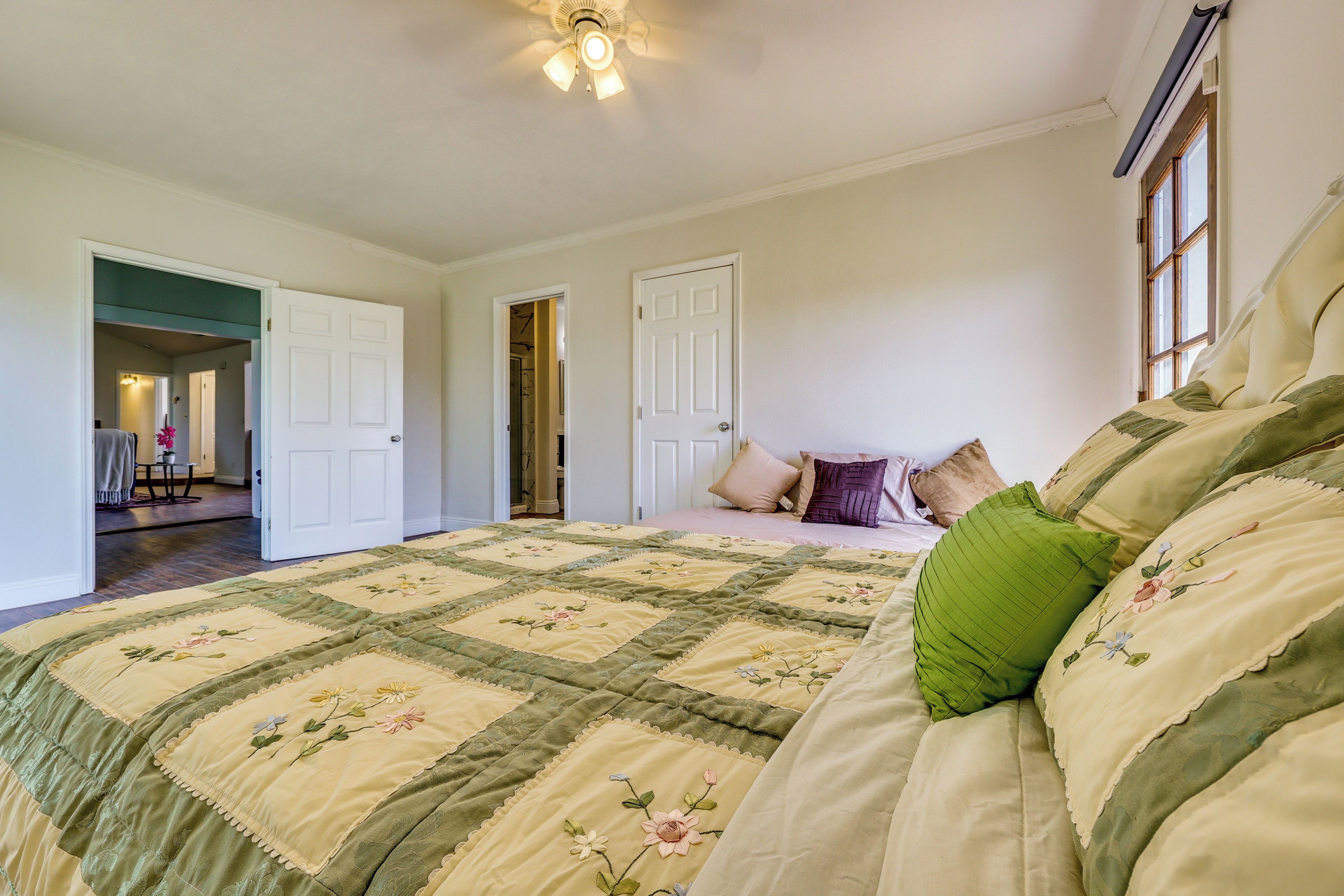 A bedroom with a large bed, a ceiling fan, and a window.