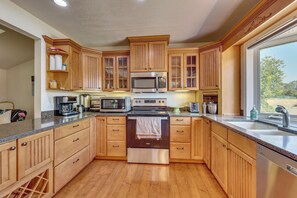 A kitchen with wooden cabinets, stainless steel appliances, and a large window. - Private Pool! Charming Clovis Escape (Clovis)