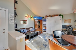 Un espacio habitable compacto con sofá, mesita de centro y zona de comedor con una silla y mesa.