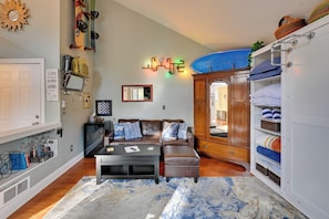 A cozy living room with a sofa, coffee table, and a surfboard on the wall. - 1 Mi to Sunriver Resort! Studio w/ Hot Tub Access (Bend)