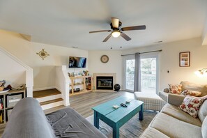 A living room with a sofa, a coffee table, a TV, a fireplace, and a staircase. - Bayfront Haven w/ Boat Dock! 4 Mi to Bethany Beach (Ocean View)