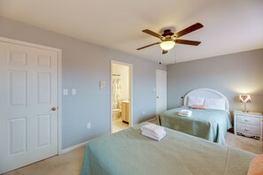 A bedroom with two beds, a ceiling fan, a nightstand, and a bathroom visible through an open door. - Bayfront Haven w/ Boat Dock! 4 Mi to Bethany Beach (Ocean View)