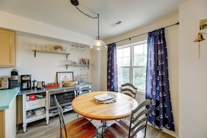 A kitchen with a wooden table, chairs, and a window with curtains. - Bayfront Haven w/ Boat Dock! 4 Mi to Bethany Beach (Ocean View)