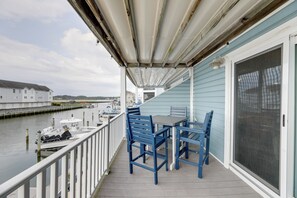 A covered outdoor area with a table and chairs, overlooking a body of water with boats and buildings in the background. - Bayfront Haven w/ Boat Dock! 4 Mi to Bethany Beach (Ocean View)
