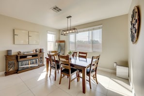 A dining area with a wooden table and chairs, a large mirror, and a decorative wall piece.