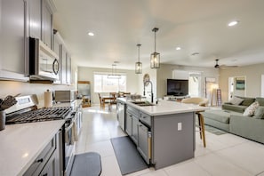 A modern kitchen with a central island, stainless steel appliances, and pendant lighting.