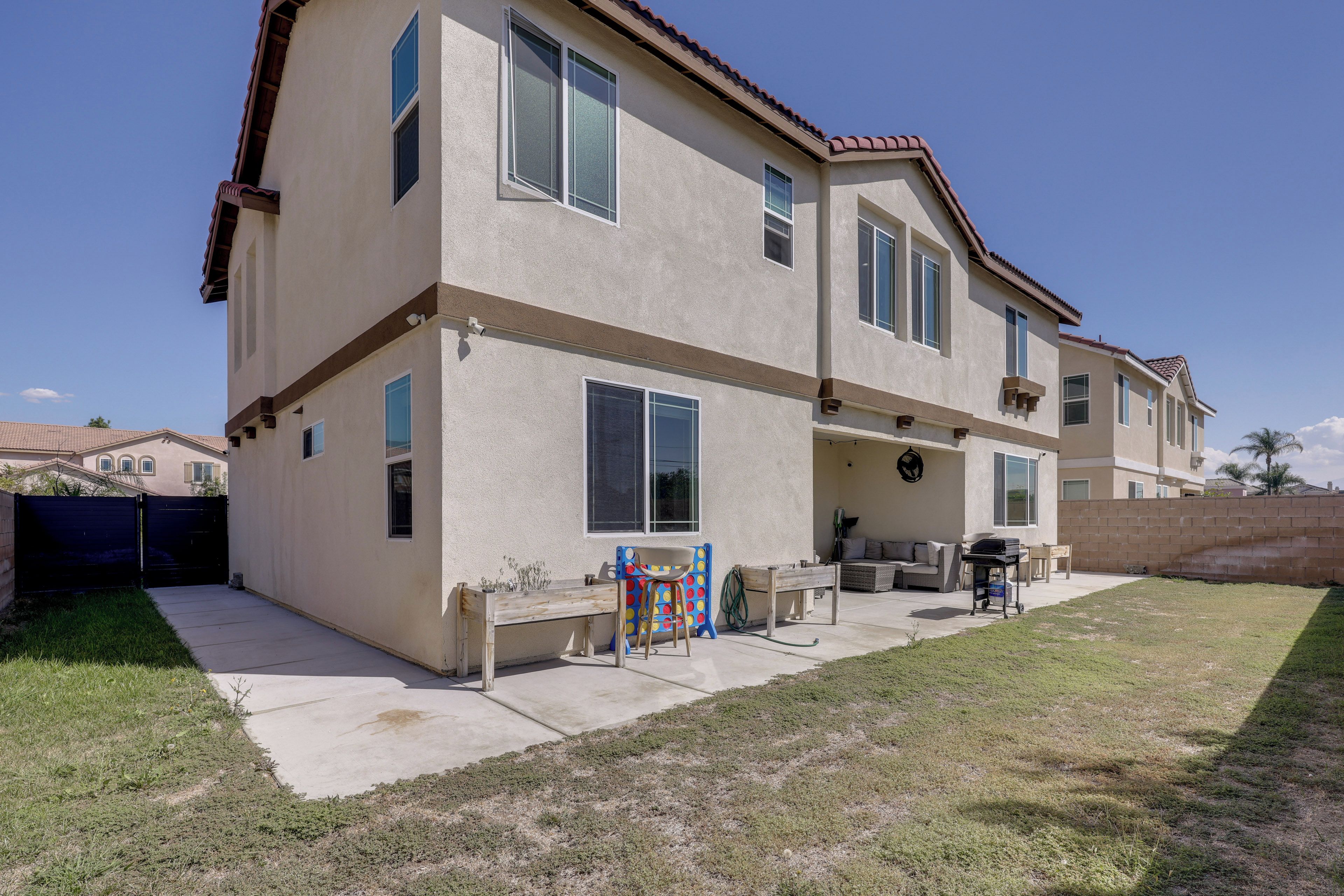A two-story house with a patio area, a grill, and outdoor furniture.