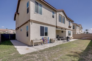 A two-story house with a patio area, a grill, and outdoor furniture.