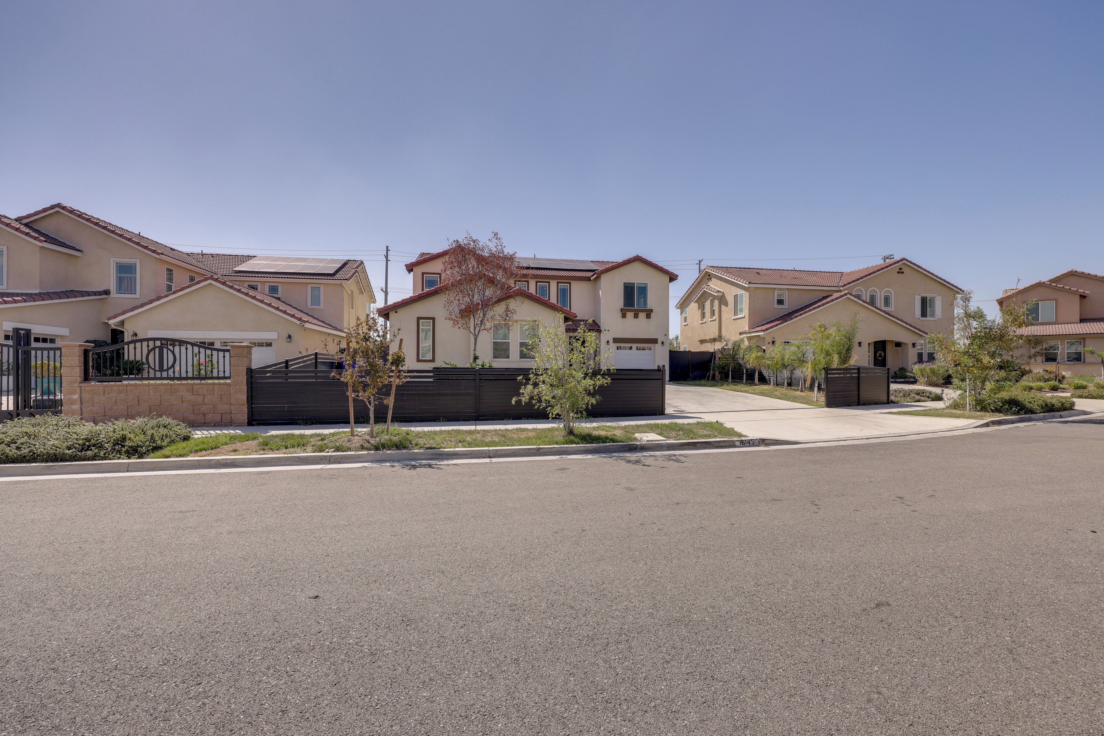 A residential street with houses featuring a uniform architectural style, a clear sky, and a well-maintained road.