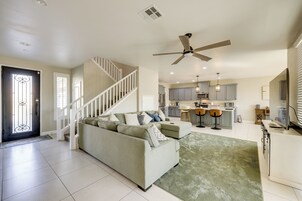 A spacious living area with a sofa, a staircase, and a kitchen in the background.