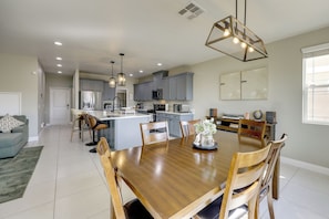 A spacious kitchen with modern appliances, a dining area with a wooden table and chairs, and a living room with a sofa and a coffee table. - Large Family Home in Fontana! Shop, Dine & Explore (Fontana)