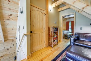 Ein gemütliches Zimmer mit Holztür, Bücherregal, Ledersofa und Esstisch.