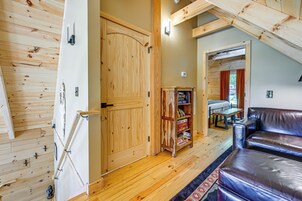Una habitación acogedora con una puerta de madera, una estantería, un sofá de cuero y una mesa de comedor.