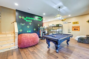 Ein Zimmer mit Billardtisch, Etagenbetten, Sitzsack und Wand mit Pixelkunst.