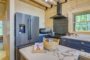 A modern kitchen with a stainless steel refrigerator, a microwave, a stove, and a marble countertop.