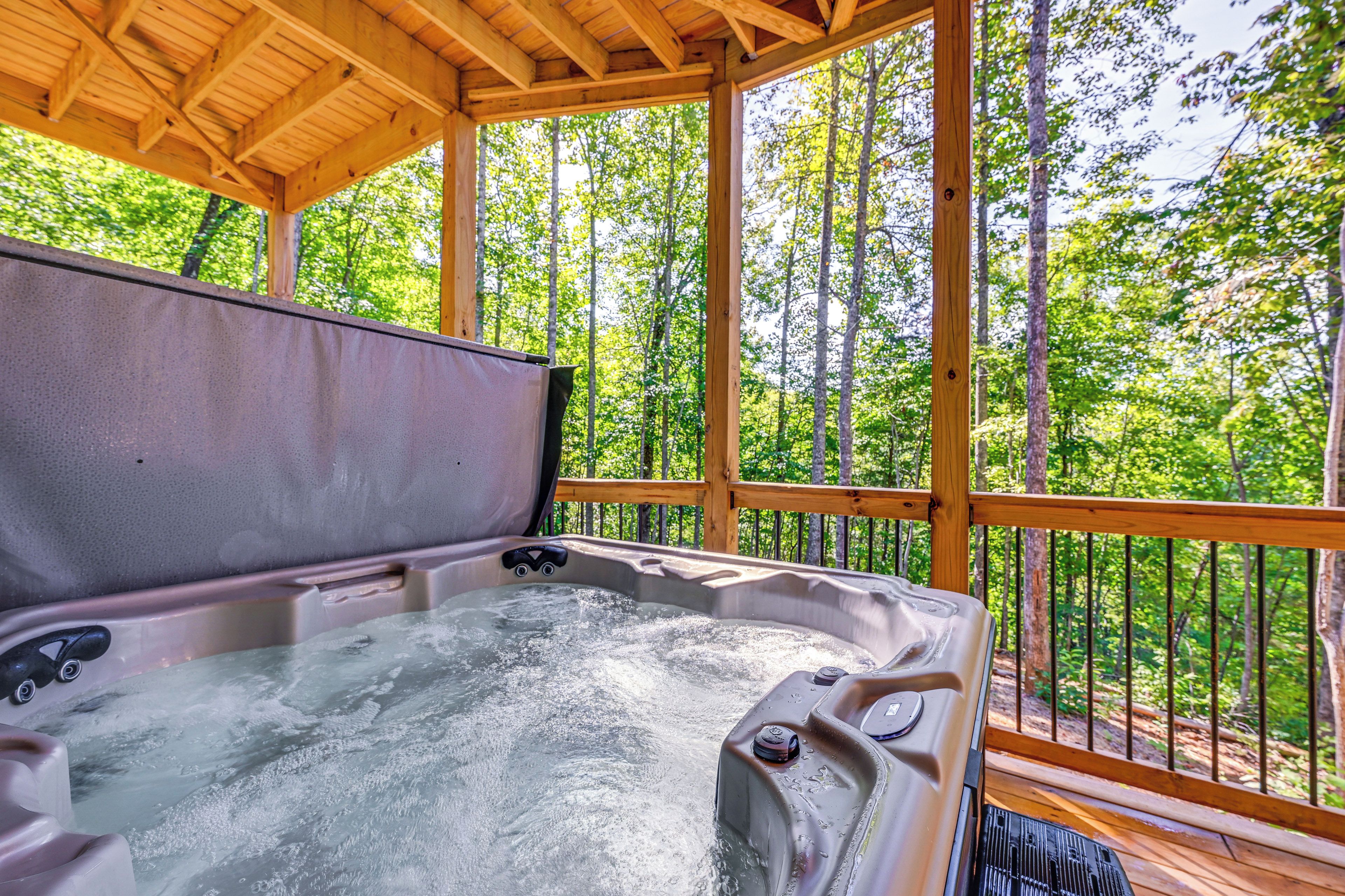 A hot tub in a wooden gazebo with a forest view.