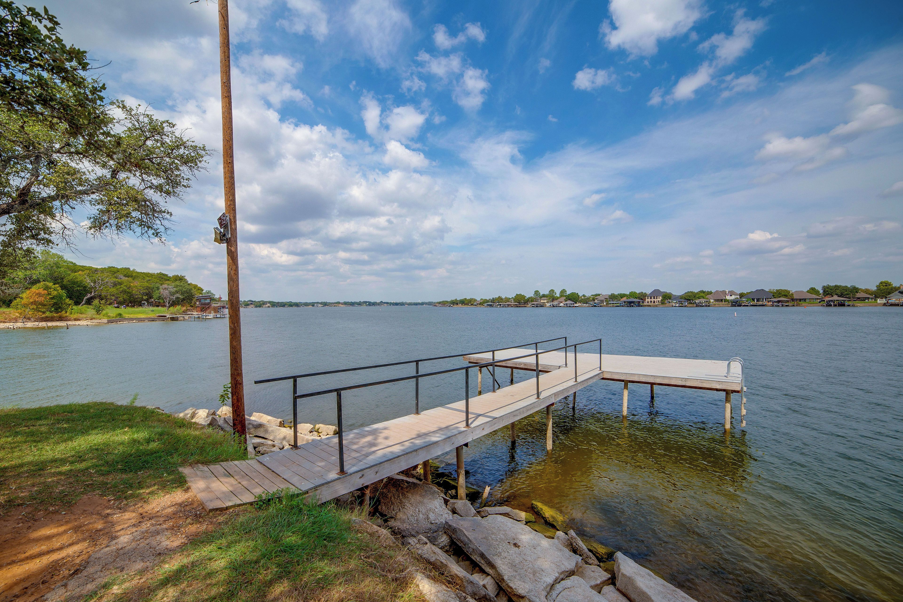 A wooden dock extending into a calm lake with a clear sky above.