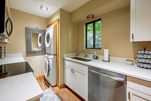 A compact kitchen with a dishwasher, a sink, and a window with a view of greenery. - Hilltop Hideaway in Sapphire Near Lake Glenville (Cashiers)