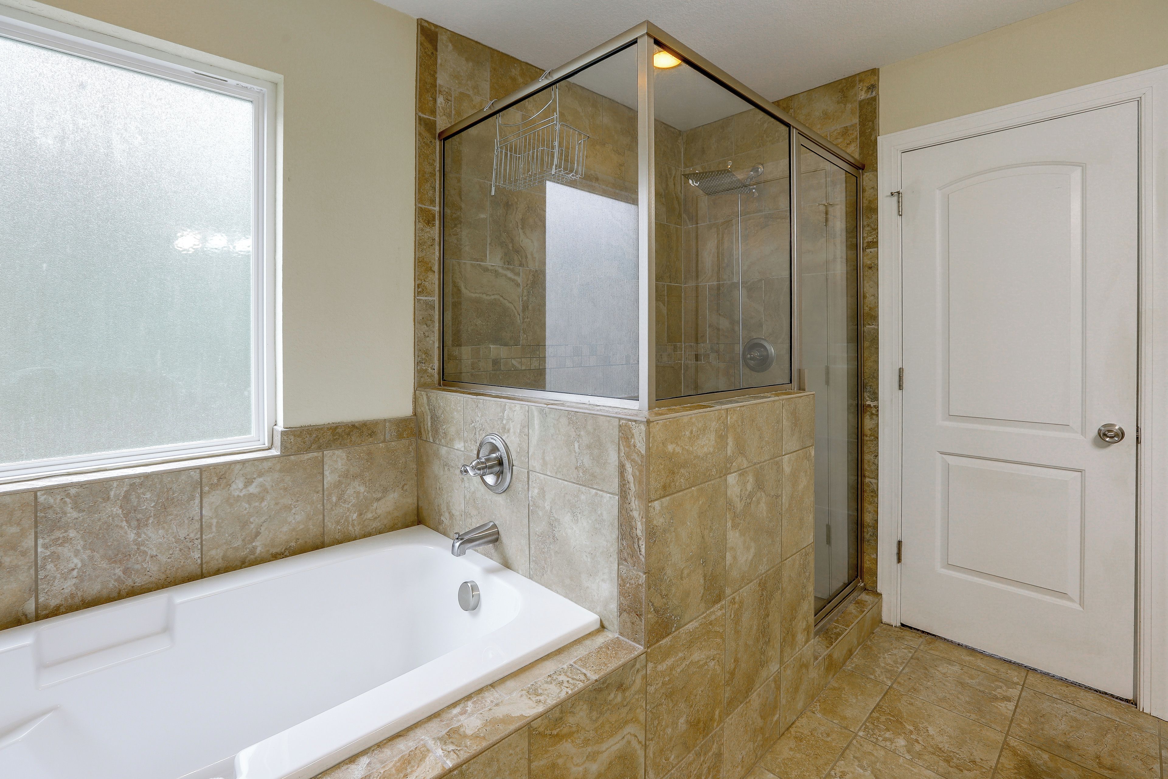A bathroom with a bathtub, a shower, and a door.