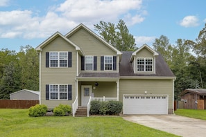 A two-story house with a front porch, a garage, and a well-maintained lawn. - Entire Home in Chesapeake, Virginia (Chesapeake)