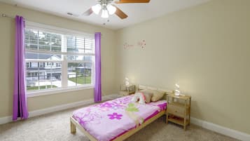 A bedroom with a bed, a nightstand, a ceiling fan, and a window with purple curtains.