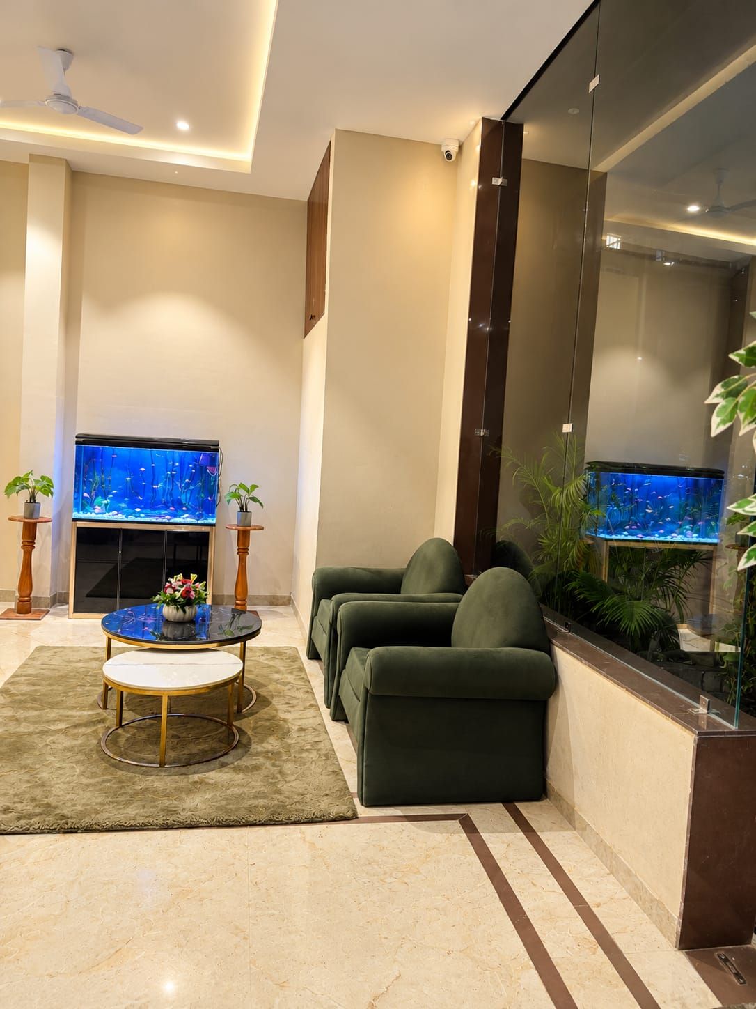 A modern living room with a fireplace, green sofas, a coffee table, and two aquariums.