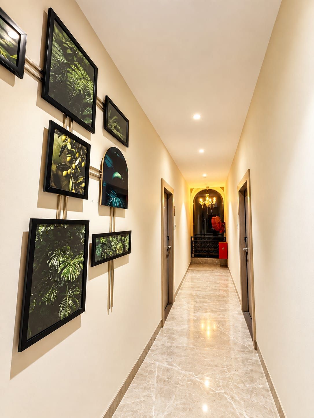 Un pasillo decorado con arte botánico enmarcados, que conduce a una escalera con un detalle en rojo.