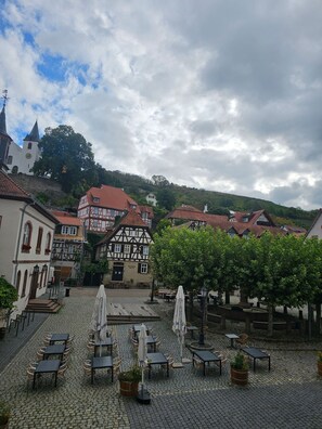 A cobblestone courtyard with outdoor seating, traditional half-timbered buildings, and a church in the background. - Apartment Neugasse – Central Location in Zwingenberg, 3 Bedrooms, Up to 6 Guests (Zwingenberg)