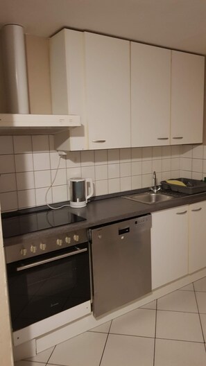 A kitchen with white cabinets, a stove, a dishwasher, and a coffee maker. - Apartment Neugasse – Central Location in Zwingenberg, 3 Bedrooms, Up to 6 Guests (Zwingenberg)