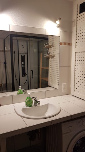 A bathroom with a white sink, a mirror, a shower, and a wall-mounted drying rack. - Apartment Neugasse – Central Location in Zwingenberg, 3 Bedrooms, Up to 6 Guests (Zwingenberg)