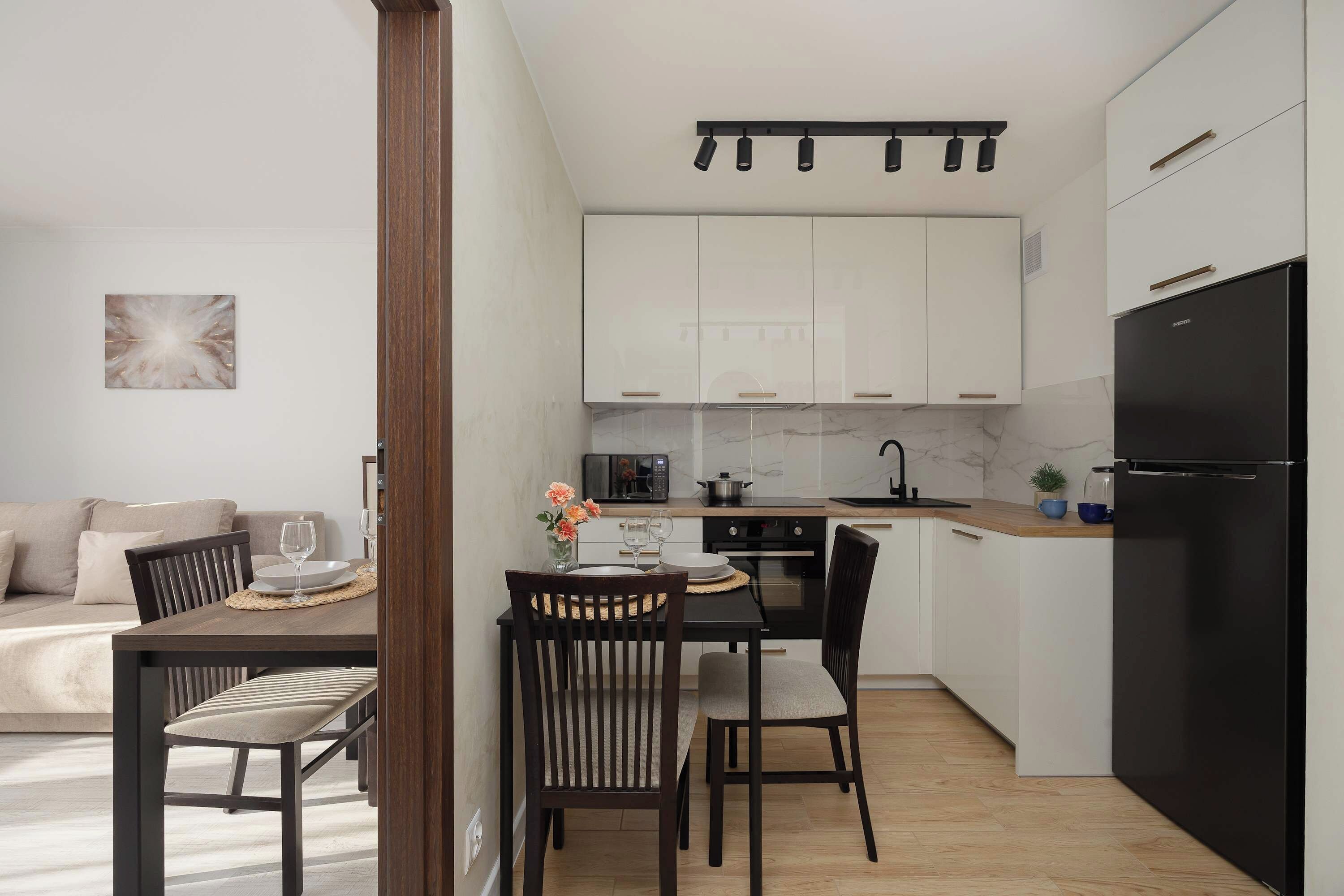 Bright and efficient, the kitchen offers ample storage in its white cabinets, alongside a charming dark wood dining table set.